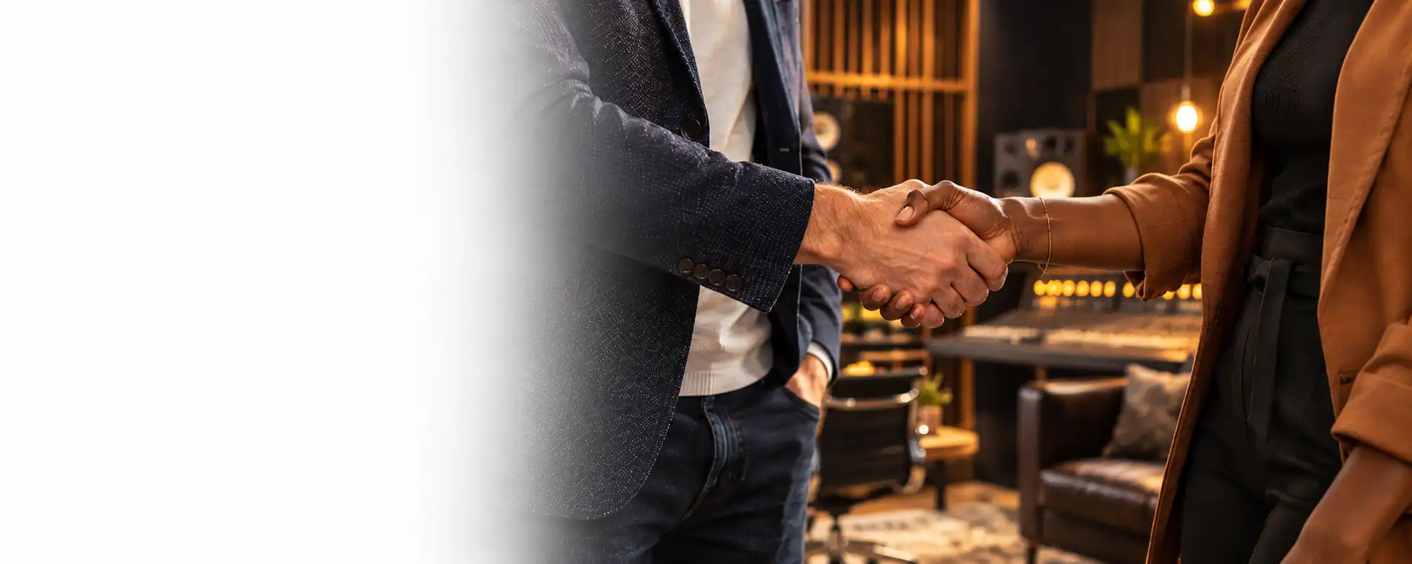 Two people shaking hands in a professional recording studio.