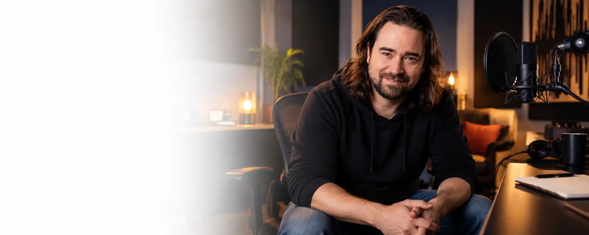 Voice artist seated in a home-style recording studio with a microphone and warm lighting.
