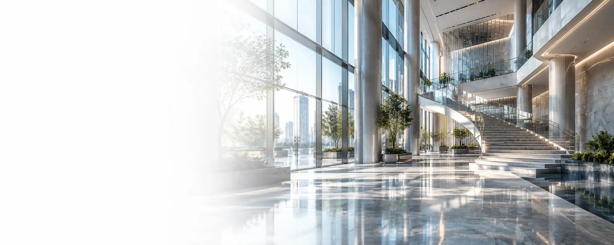Bright contemporary office atrium with glass walls and a broad staircase.